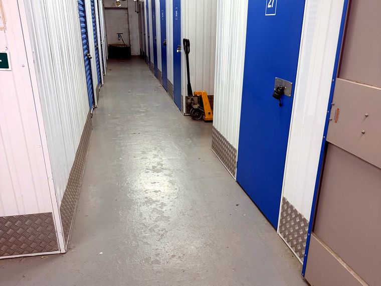 A corridor of blue storage unit doors inside the Knightcott Self Storage building